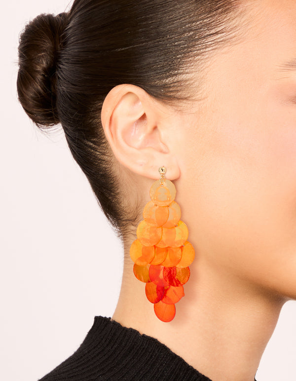 Crafted from genuine orange shell, these layered disc waterfall drop earrings feature statement styling in coral and peachpuff hues on ear view