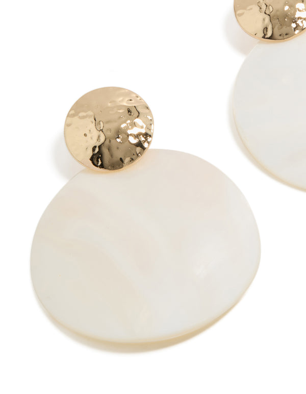 Featuring statement drop earrings with hammered gold and white genuine shell close up view