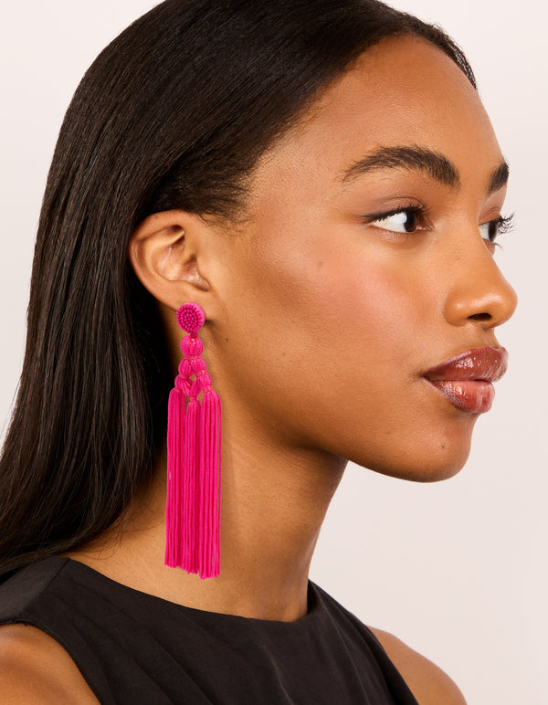 Displaying statement hot pink fabric tassel drop earrings with beads styled beautifully on model view