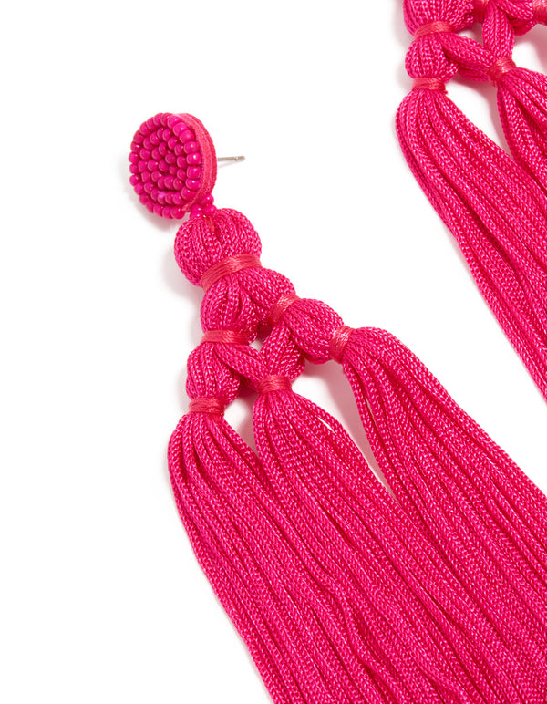 Designed with hot pink fabric, these statement drop earrings showcase beads and tassel elements close up view