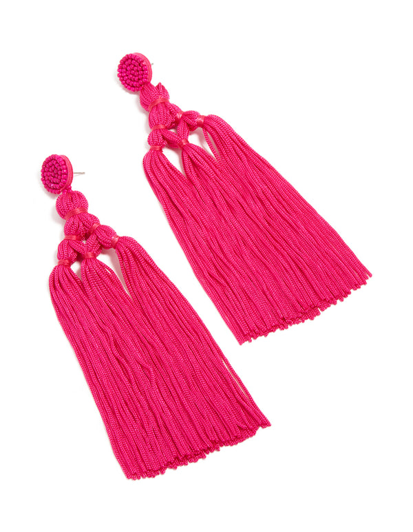 Crafted from hot pink fabric, these statement drop earrings feature beads and tassel detailing front view