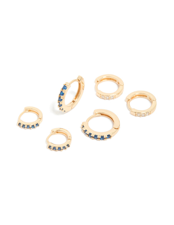 Showcasing a set of gold huggie earrings featuring clear and sapphire cubic zirconia in a 3-pack front view