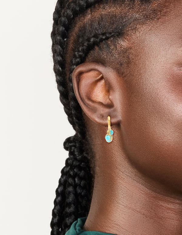 These chunky huggie earrings with charm accents in waterproof stainless steel showcase turquoise and gold plating on ear view