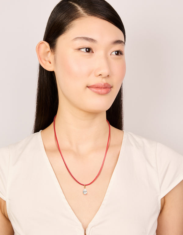 Designed with pear cut crystal cubic zirconia waterproof gold plated stainless steel pendant necklace on coral red cord on model view