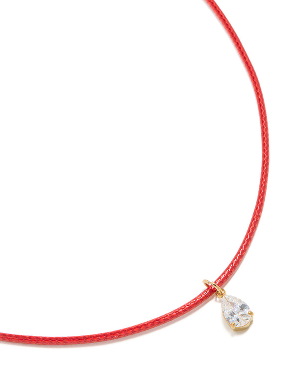 Showcasing a pear cut crystal cubic zirconia waterproof gold plated stainless steel necklace with pendant on red cord close up view