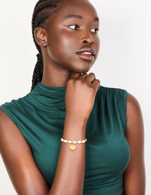 A waterproof gold plated stainless steel freshwater pearl and shell, ball bracelet with beads, ocean accents, and statement styling on model view