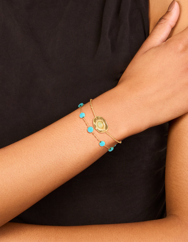 Crafted from waterproof beaded stainless steel disc with turquoise semi precious stone and green accents in gold plated finish on wrist view