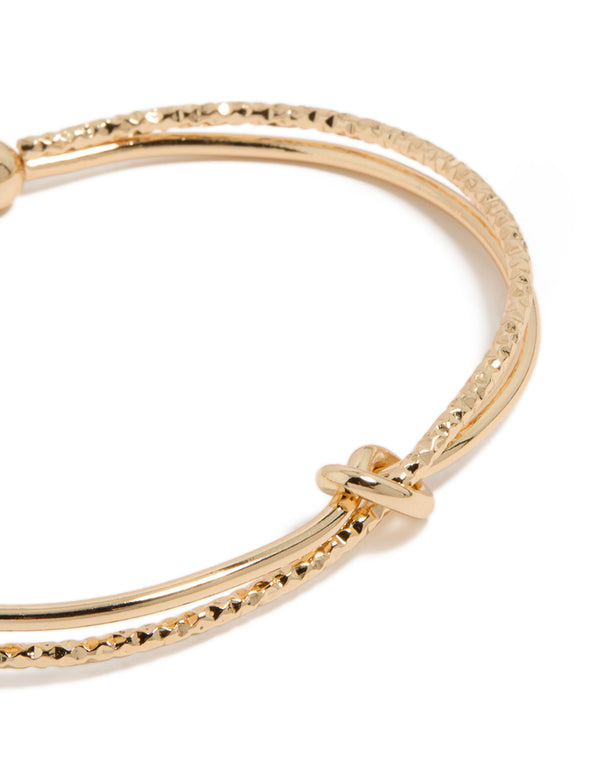 Featuring a gold textured and smooth knotted wrist cuff bangle close up view