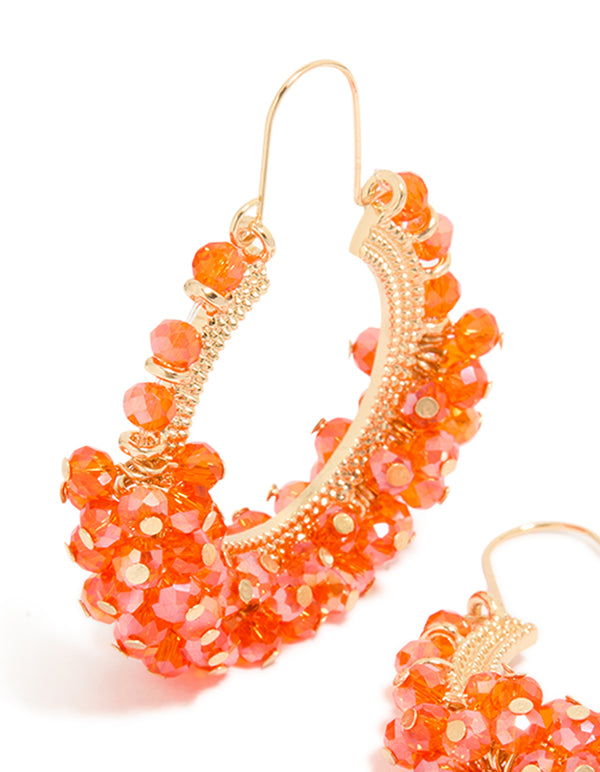 Showcasing statement hoop earrings with beads in coral and gold accessories close up view