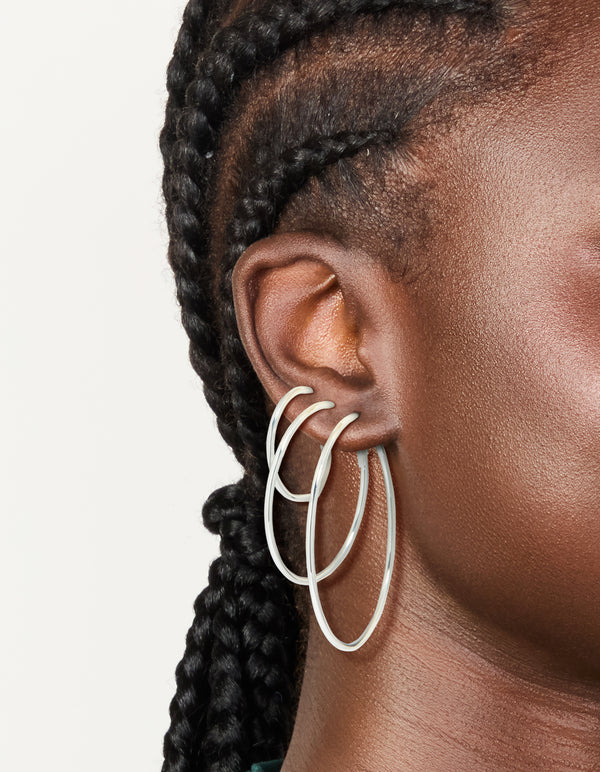 Showcasing silver plated plain hoop earrings in a 3-pack on ear view