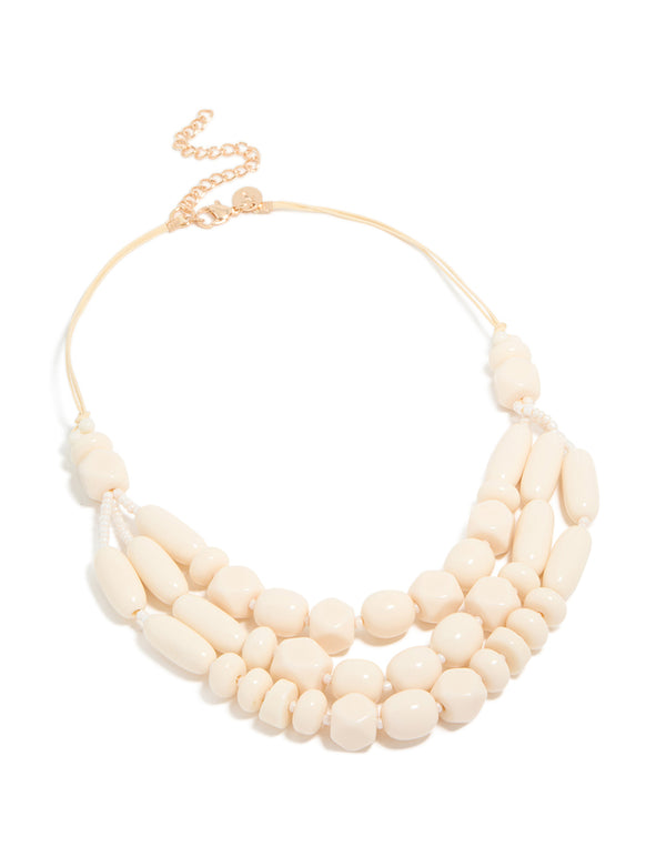 Discover a beaded acrylic yarn necklace in cream and gold tones front view
