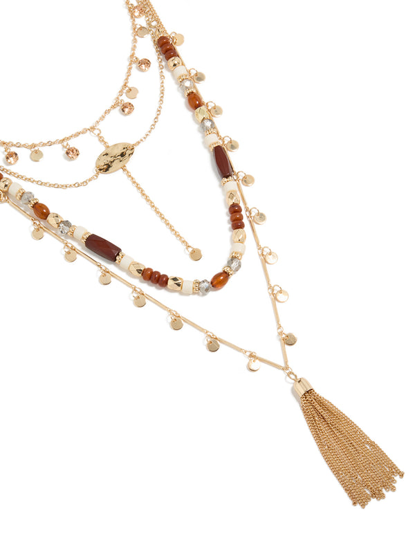 Discover a statement necklace with beads, tassel, charm and disc pendant in gold close up view