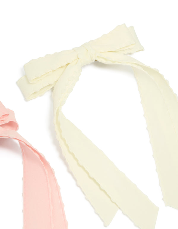 Crafted with scalloped edges, this 2-pack of fabric bow clips in solid light pink and ivory side view