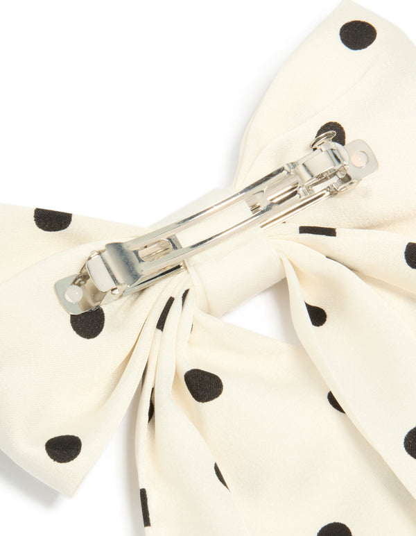 Featuring a white and black polka dot fabric bow hair clip detail view