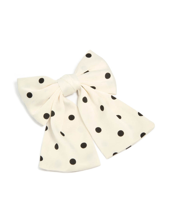 Showcasing a white and black polka dot fabric bow hair clip front view
