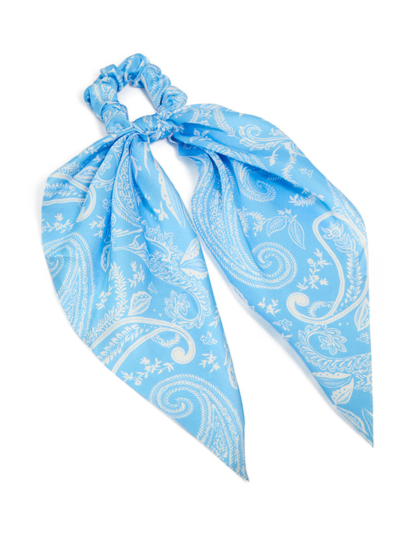 Showcasing a light blue paisley printed fabric scarf scrunchie featuring leaf details in white front view