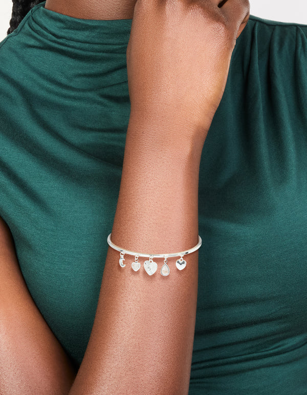 Featuring a silver plated moon and heart charm toggle bangle with celestial accents on wrist view