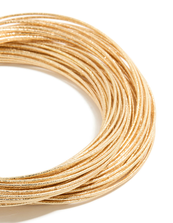 This multi crossover bangle features worn gold finish in close up view