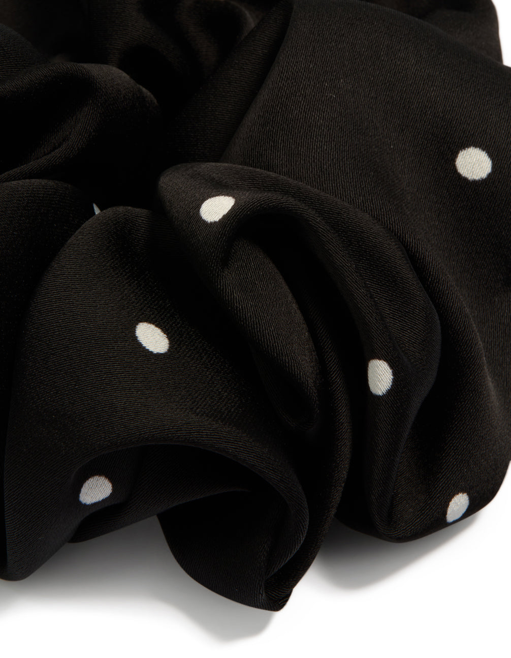 Crafted from polka dot patterned fabric, this statement scrunchie features micro dots in black and white detail view