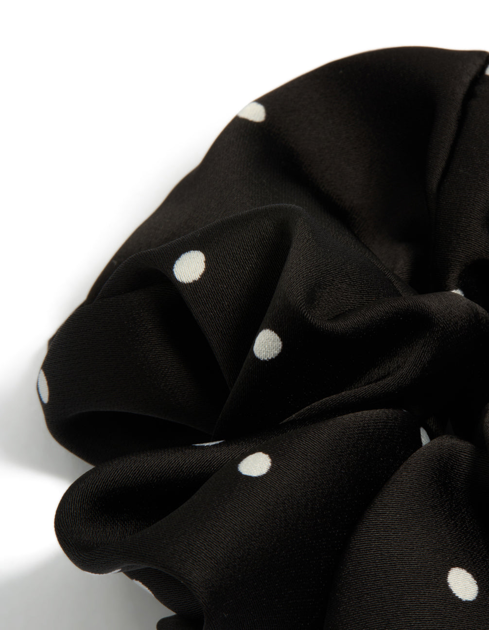 Designed with micro polka dot pattern, a statement scrunchie in black and white fabric side view