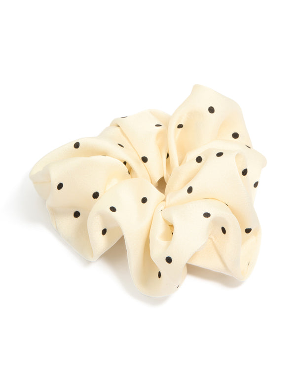 Crafted from fabric with polka dot pattern in cornsilk and black statement scrunchie front view