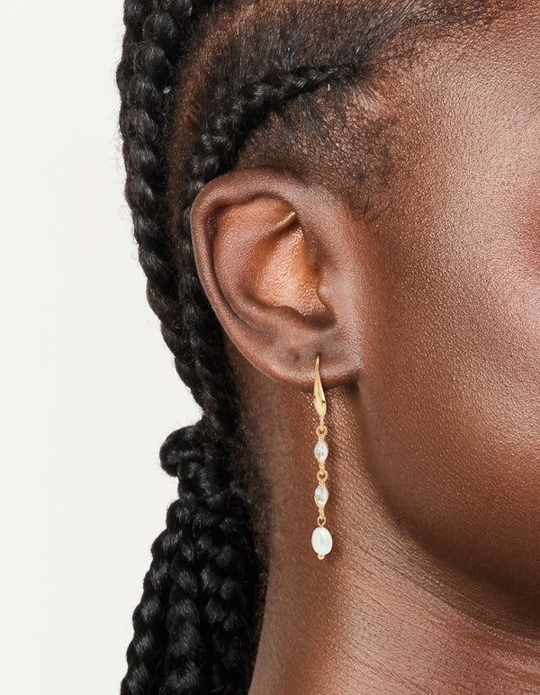 Showcasing cubic zirconia and freshwater pearl hook drop earrings in gold plated finish on ear view
