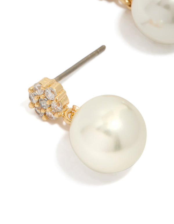 Detailed view of gold plated small round cubic zirconia and pearl drop earrings in white highlighting craftsmanship close up view