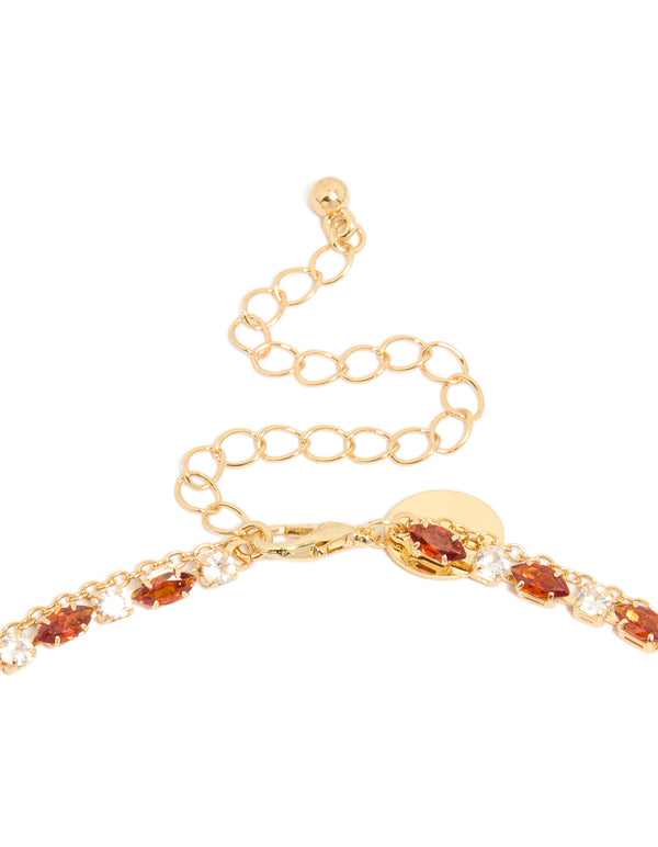 Highlighting the gold plated red cubic zirconia tennis and teardrop charm layer necklace with statement styling clasp detail view
