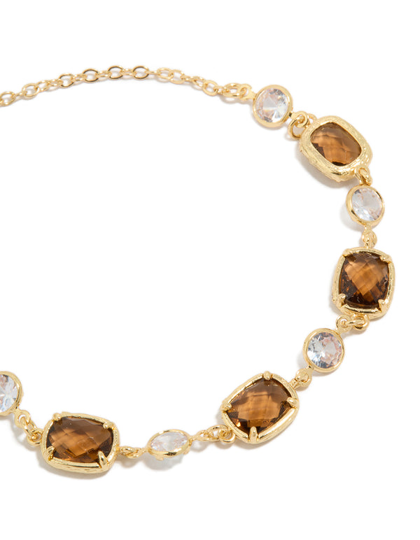 Highlighting a gold plated clear and cognac cubic zirconia square cut bezel toggle bracelet close up view