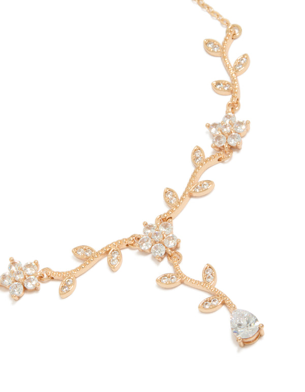 Showcasing a statement necklace with floral vine design featuring leaf accents and cubic zirconia in gold close up view