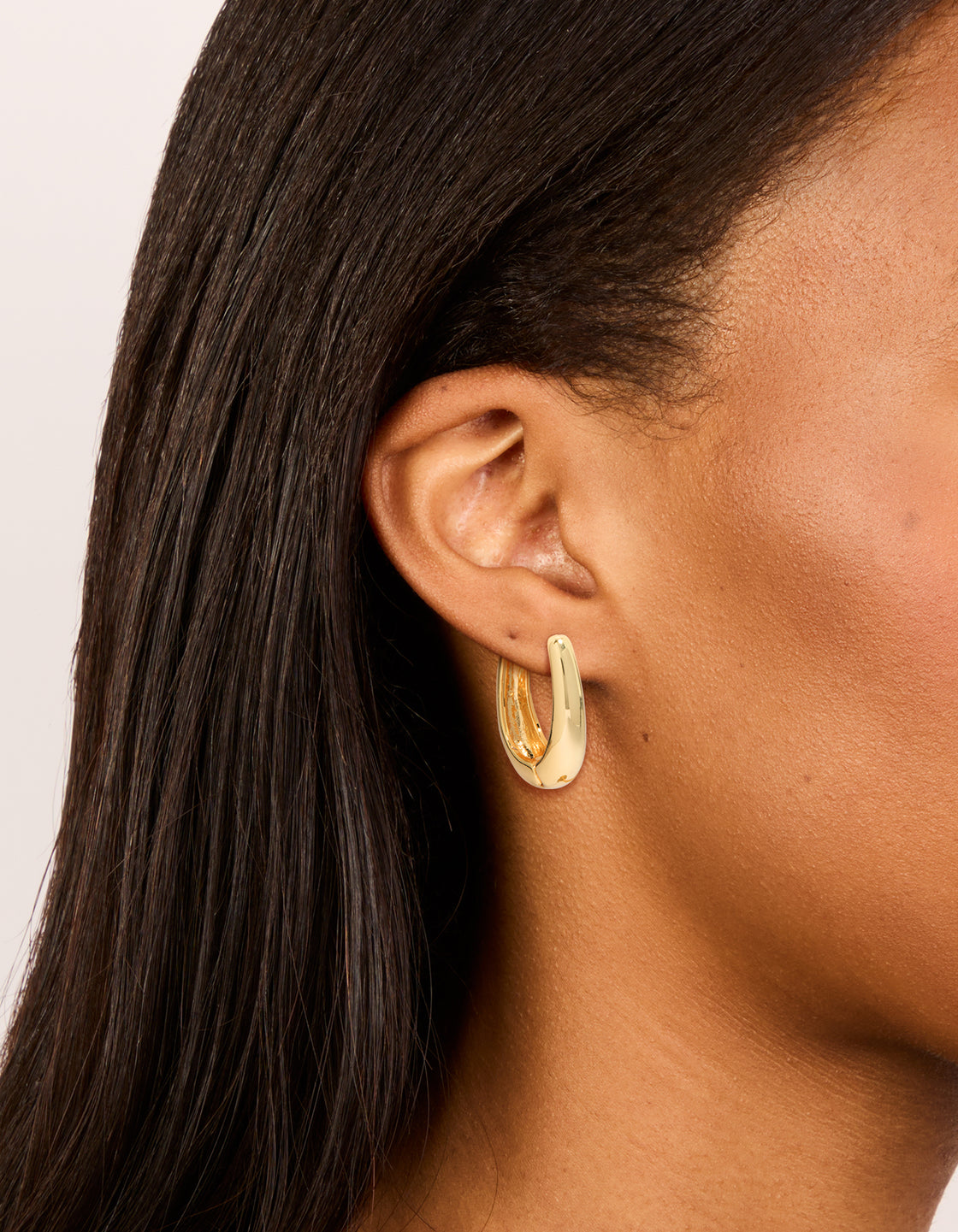 Showcasing gold plated skinny teardrop hoop earrings with closure on ear view