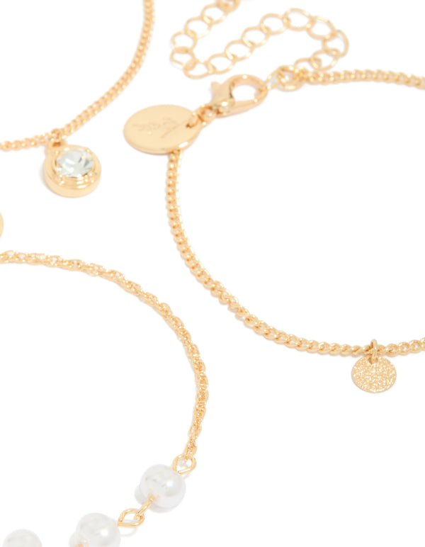 Showcasing a 3-pack of gold charm bracelets accented with pearls, discs, and a solitaire-cut diamante close up view
