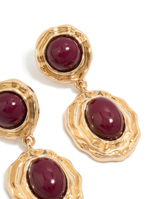 Detailed view of statement gold double burgundy resin drop earrings featuring maroon cabochons in textured settings post detail view