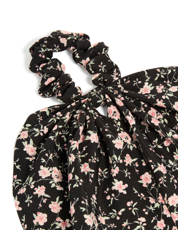 Featuring floral printed fabric in black and pink, this statement scarf scrunchie is shown in side view