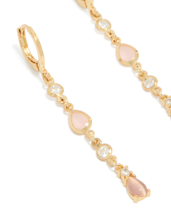 Showcasing gold plated cubic zirconia trio and pink catseye drop huggie earrings close up view