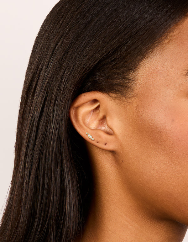 Discover dainty vine design flat back stud earrings crafted from gold plated surgical steel featuring marquise cut cubic zirconia stones on ear view