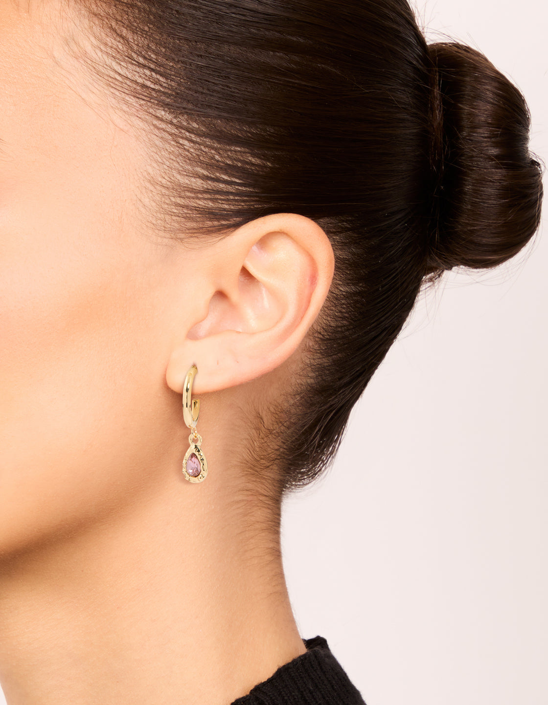Featuring gold blue and pink diamante huggie earrings in a 3-pack on ear view