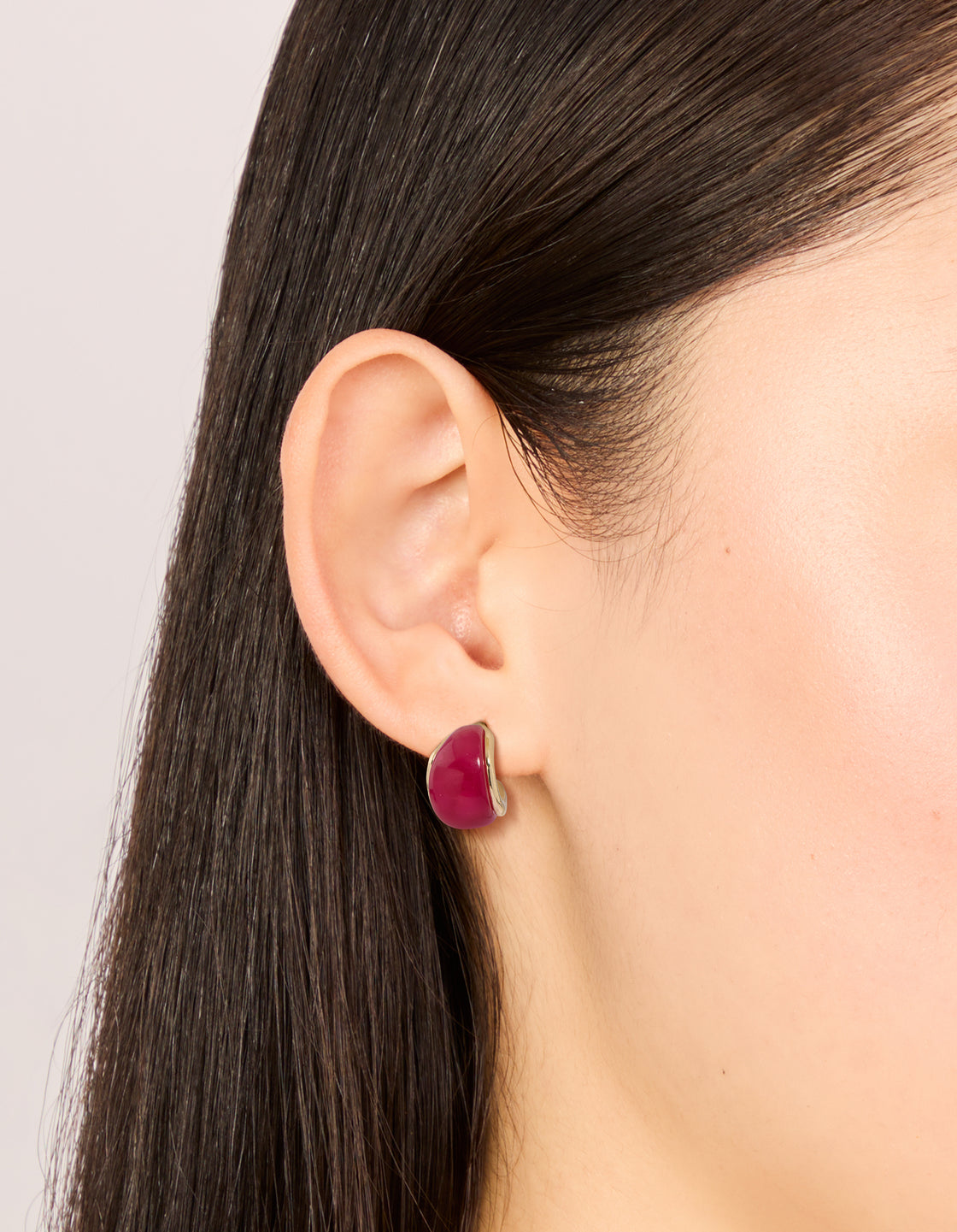 Displaying chunky hoop earrings in a 3-pack with red, pink, and beige acrylic bubble design featuring gold accents on ear view