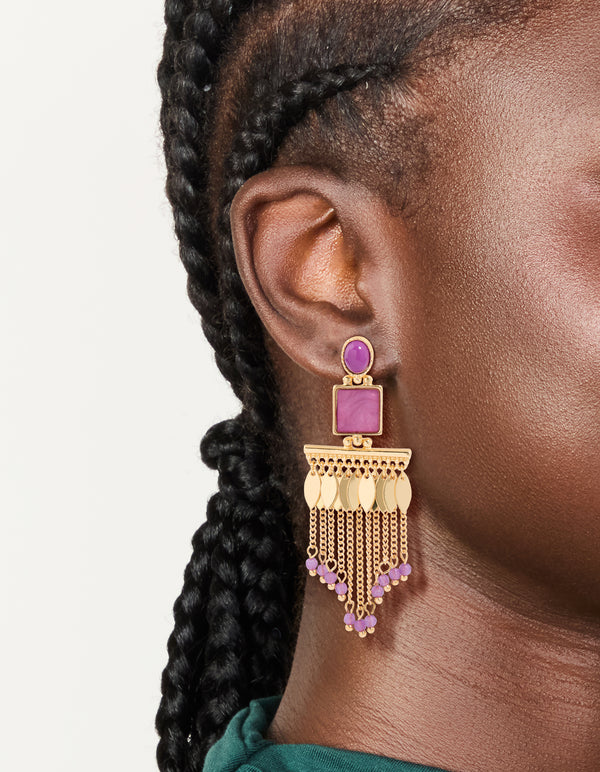 Beautifully crafted gold statement drop earrings with purple beaded chain tassels, and leaf charm accents on ear view