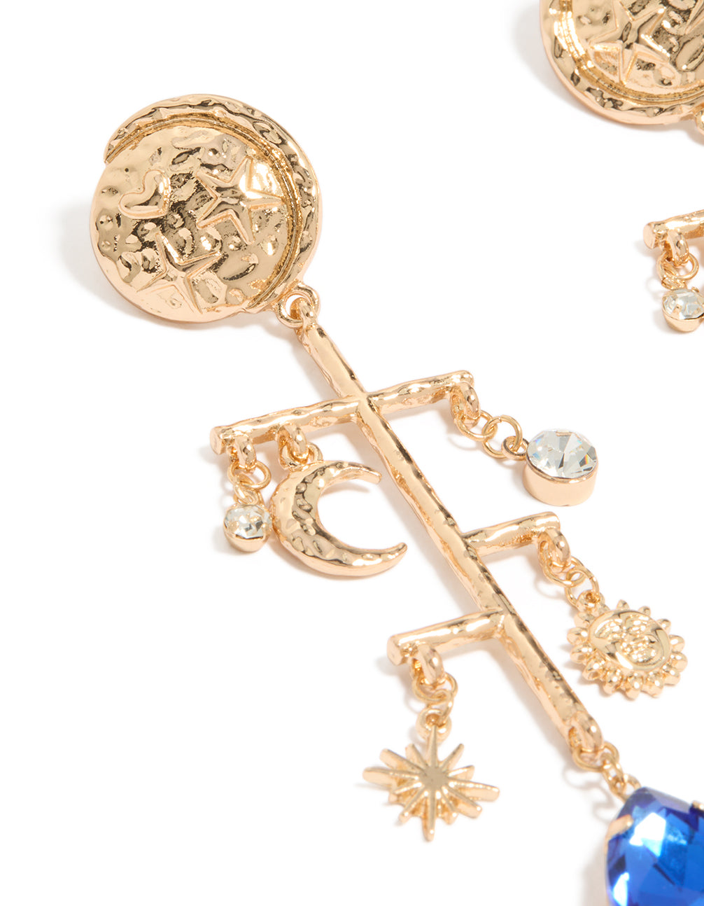 Featuring worn gold celestial marble drop earrings with charm elements, moon, sun, star motifs, and royal blue teardrop gemstone close up view