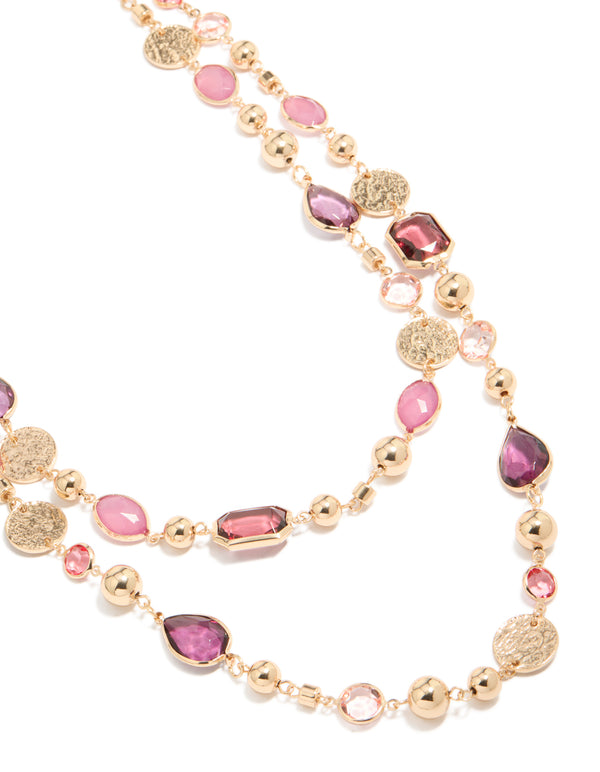 Beautifully crafted gold disc and pink beaded layered long necklace featuring charms in coral and purple accents in a chunky style close up view