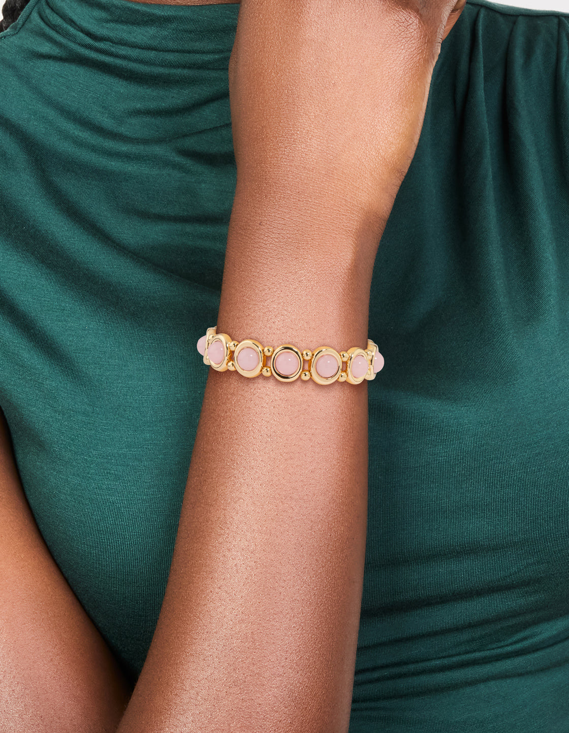 Featuring beaded organic shaped stretch bracelet in gold with pink accents on wrist view