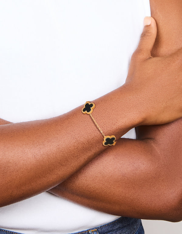 Featuring a waterproof gold plated stainless steel black clover chain bracelet with charm accents in a dainty style on wrist view