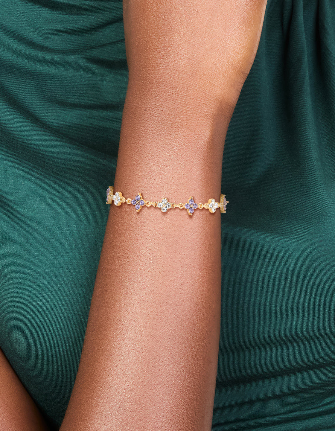 Highlighting a floral bracelet crafted from gold plated materials with cubic zirconia in purple on wrist view