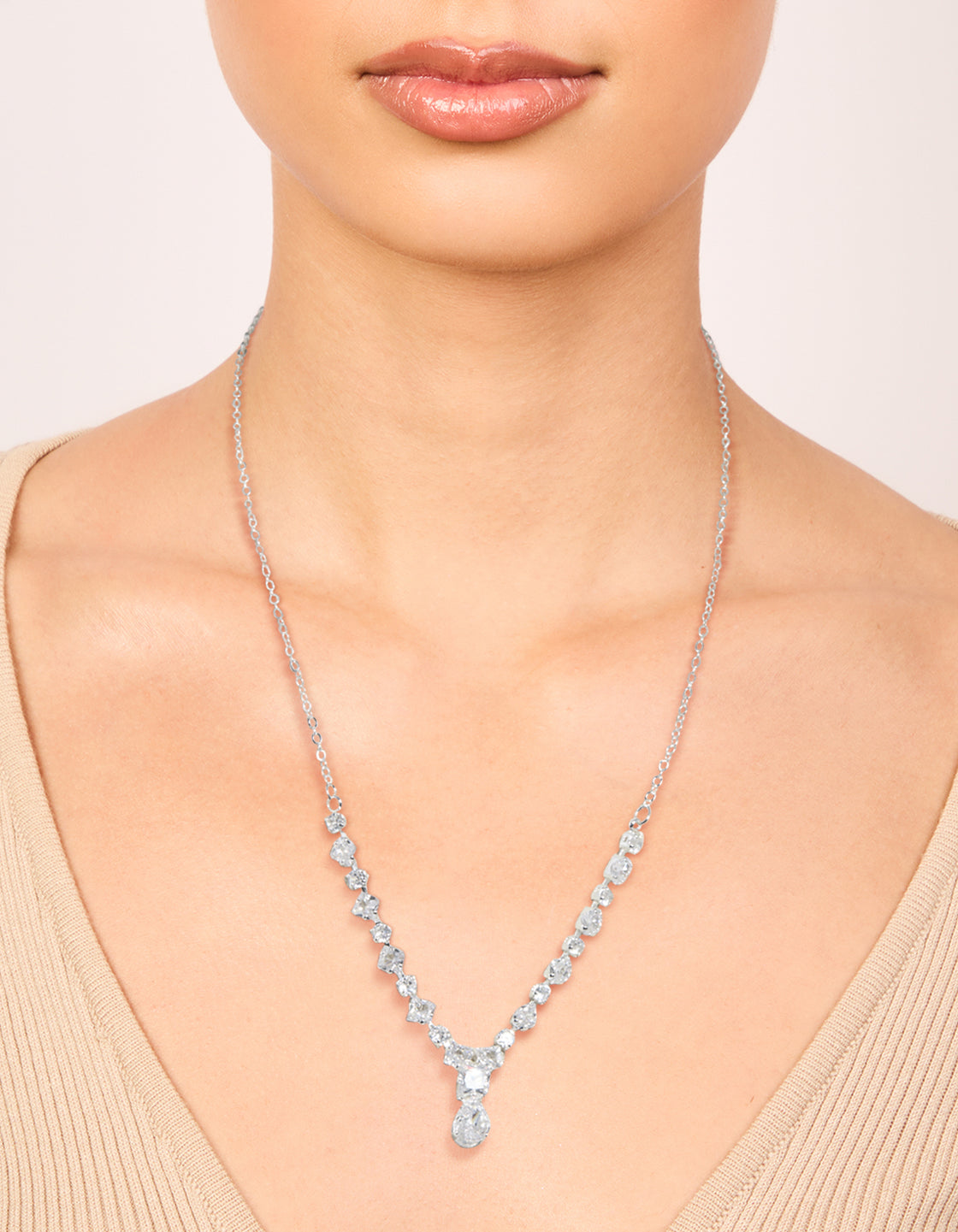 Showcasing a small graduating cubic zirconia Y-necklace in silver plated metal with dainty style on neck view