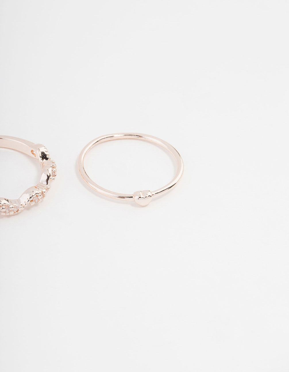Highlighting rose gold plated rings with mini bow and heart accents featuring cubic zirconia in a 3-pack close up view