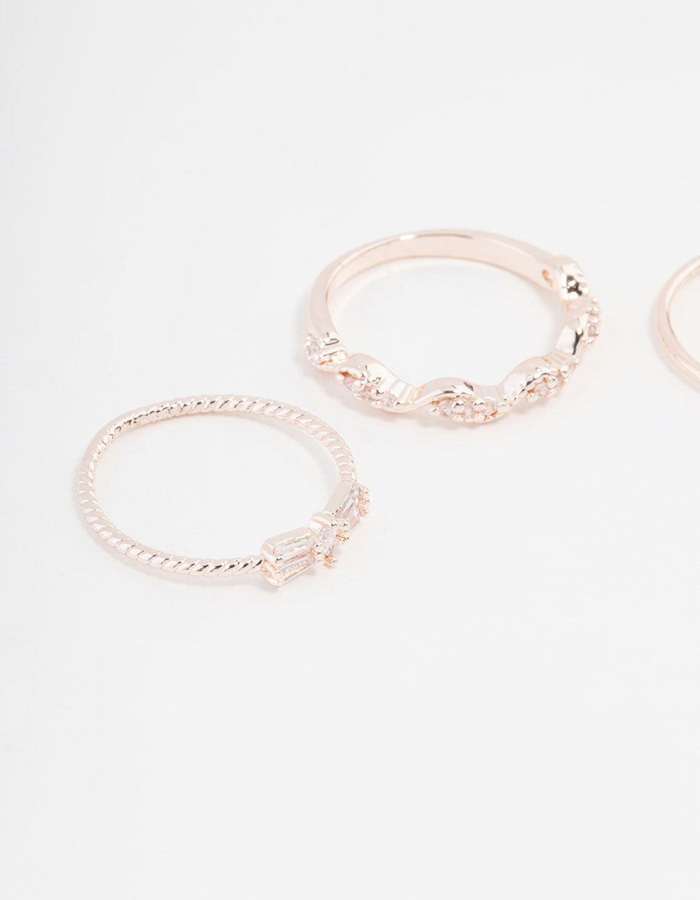 Highlighting rose gold plated rings with mini bow and heart accents featuring cubic zirconia in a 3-pack close up view