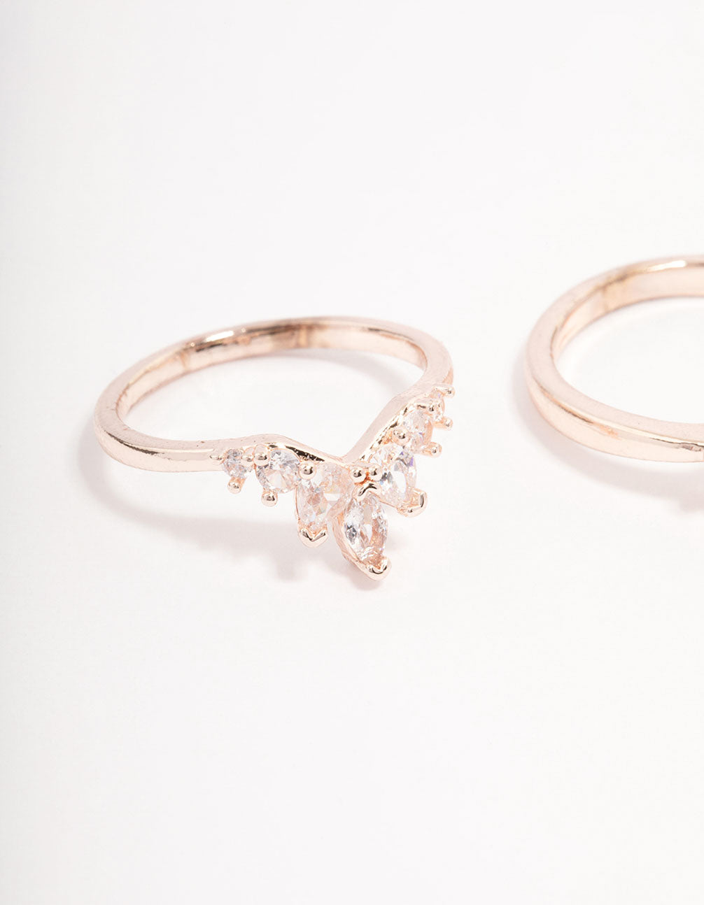 Highlighting charm embellished rose gold arched dainty rings close up view