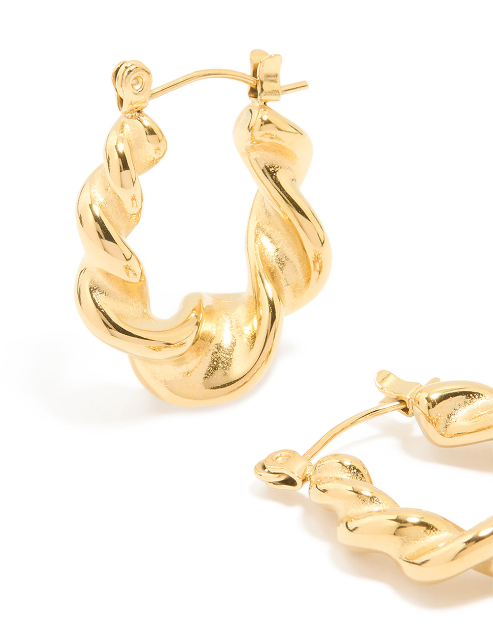 Featuring large twisted statement hoop earrings in waterproof gold plated stainless steel with smooth texture close up view