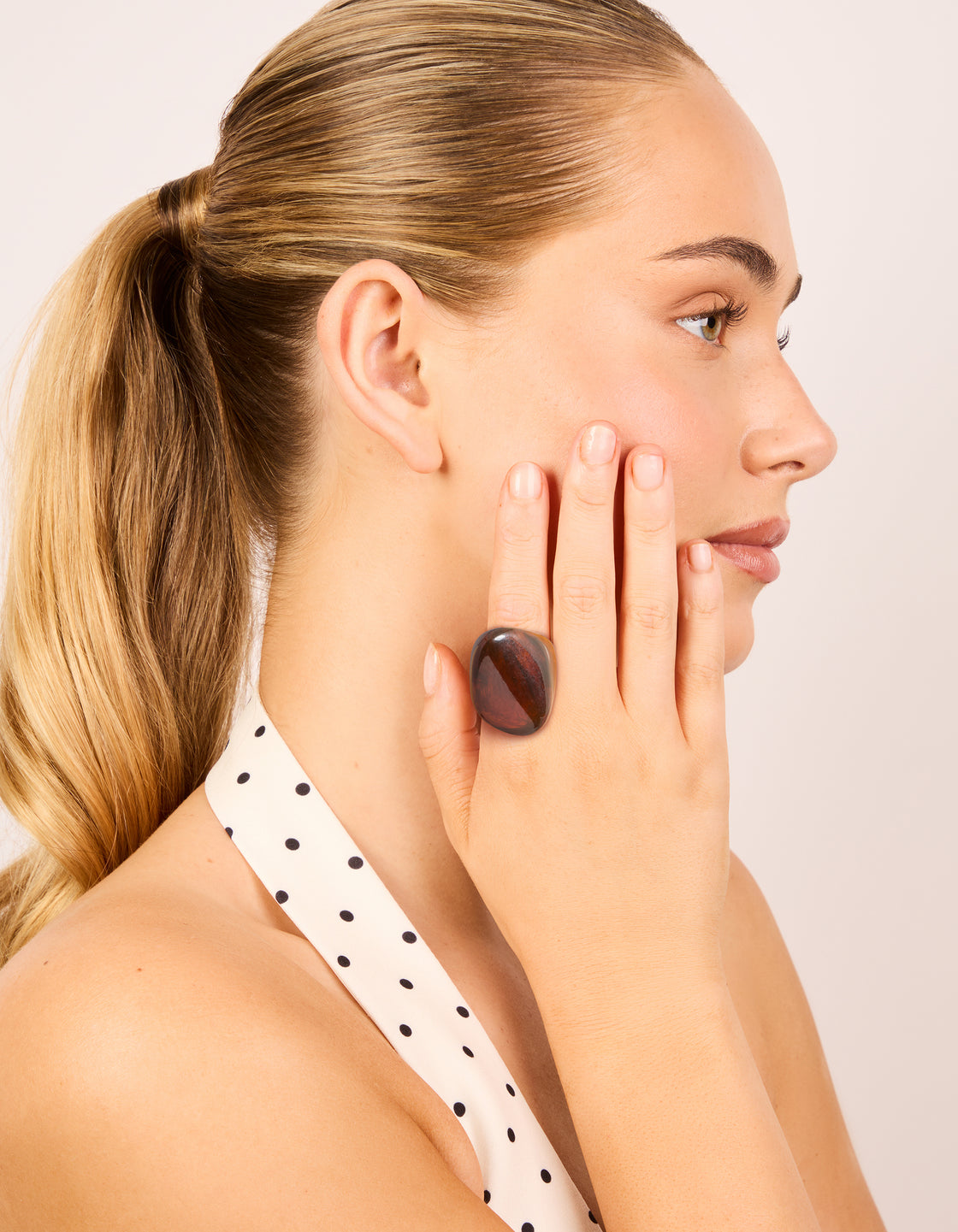 Showcasing a dark brown acrylic large obtuse ring in chunky statement style on finger view